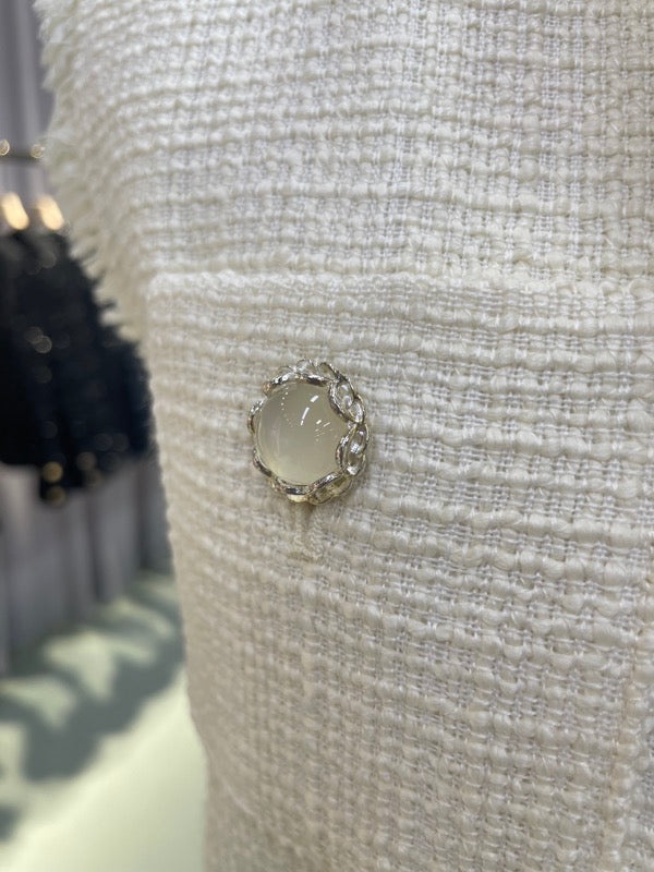 Decorative button against the white woven tweed of the 70816 vest