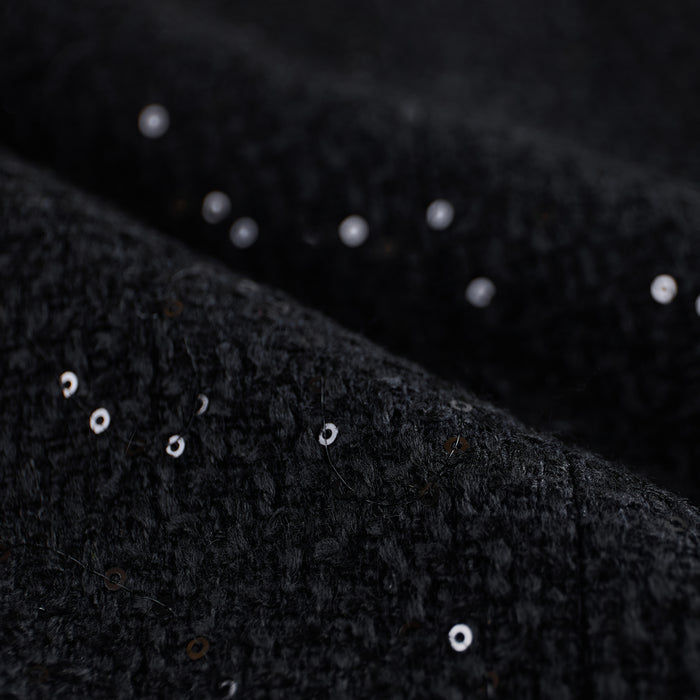 Close-up of black textured tweed with scattered sequins