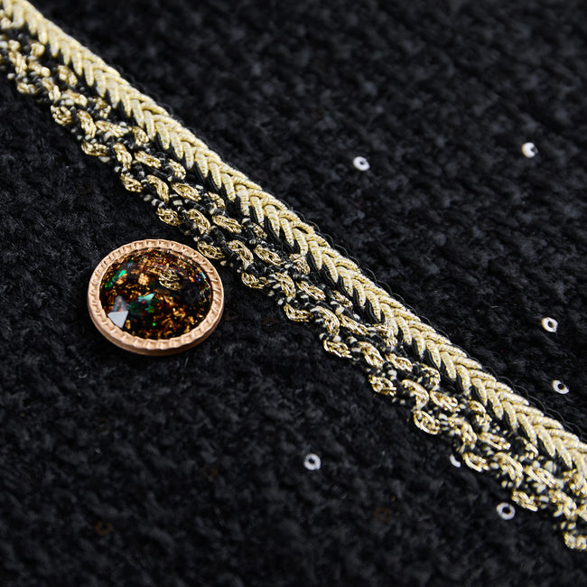 Close-up of an amber-toned jewel-style button beside braided trim